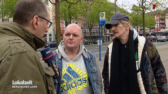 Ein Reporter redet mit zwei Männer in der Nähe einer Straße