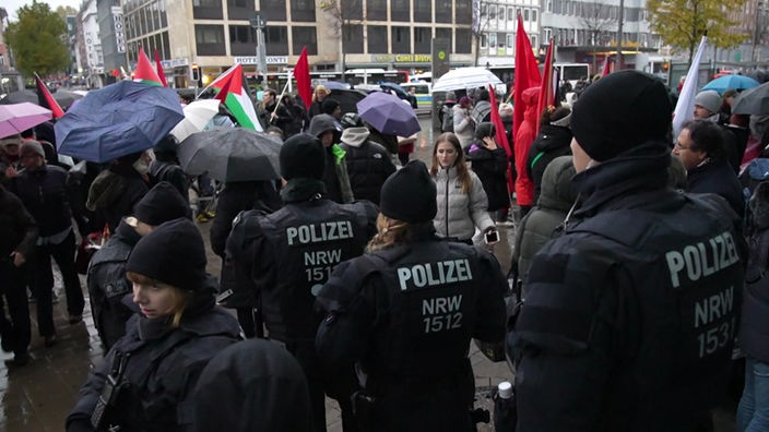 Eine Aufnahme von der Palästinenser-Demo in Münster: Es sind mehrere Polizist:innen und Personen mit der Flagge Palästinas zu sehen.