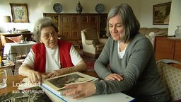 Zwei Frauen schauen in ein Fotoalbum