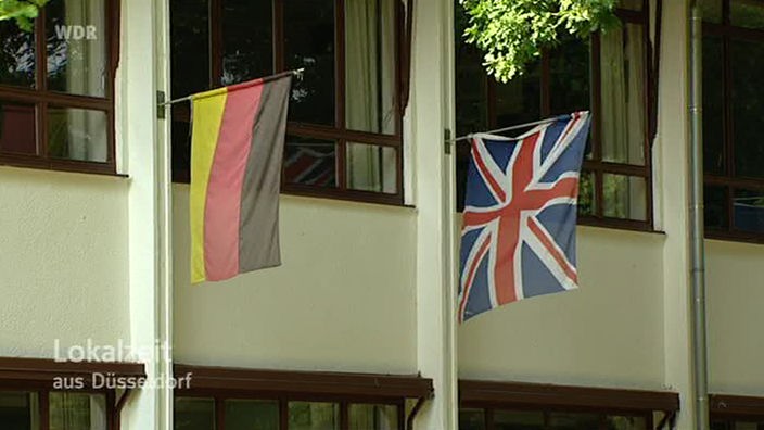 Deutsche und britische Fahne an einer Hauswand.