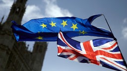 Eine EU-Flagge und eine britische Nationalflagge wehen vor dem britischen Parlament im Palace of Westminster. 