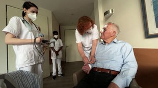 Pflegefachkräfte unterhalten sich mit einem Patienten