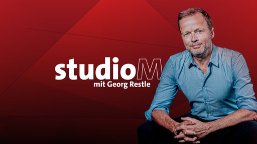 Redakteur und Moderator Georg Restle vor rotem Hintergrund, auf dem Bild der Schriftzug "studioM mit Georg Restle"