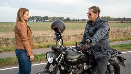 Ein Mann sitzt auf einem Motorrad und daneben steht eine Frau.