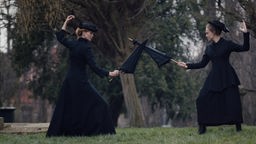 Spielfilmszene, in der die britische Frauenrechtlerin Emmeline Pankhurst und ihre Tochter Christabel mit Regenschirmen fechten