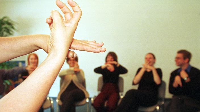 Menschen sitzen im Stuhlkreis und unterhalten sich mittels Gebärdensprache