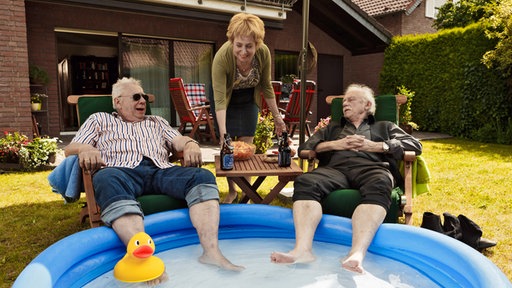 Die Füße im Planschbecken - Günter Hoffmann (Peter Lerchbaumer, l.) und Edwin Bremer (Tilo Prückner, r.) genießen den Sommer und lassen sich von Heidrun (Verena Plangger, M.) verwöhnen.