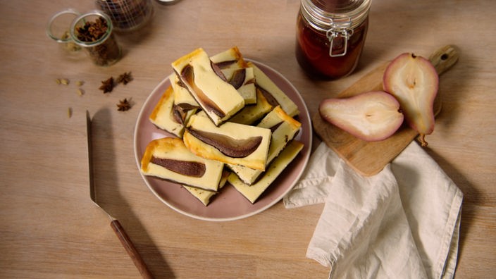 Das Bild zeigt einen Käsekuchen mit Schokoladenteig und pochierten Birnen