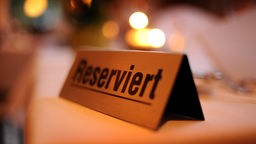 Das Bild zeigt ein Schild auf einem Restaurant-Tisch mit der Aufschrift "Reserviert". 