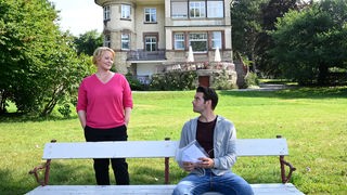 Ein Mann und eine Frau vor einer Villa am See