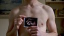 Ein Mann hält ein Ultraschallbild eines Embryos hoch.