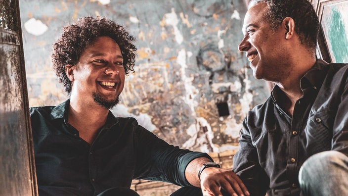 Zwei Männer in einer Bar sitzen nebeneinander und lachen sich an