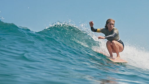 Eine junge Surferin reitet eine Welle