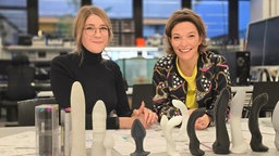 Anna Planken (r) und Alina Eynch (l) vor ihnen einen Tisch mit Edeldildos.