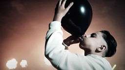 Ein Kind, das Lachgas per Luftballon einatmet