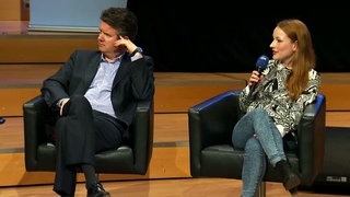 Auf einem Podium sitzen Lars Halder und Katharina Meyer, die in ein Mikrofon spricht