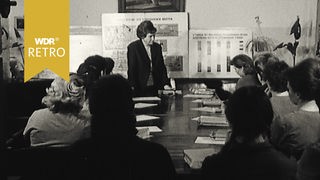 Eine Frau steht vor einer Tafel, Schwarz-Weißbild
