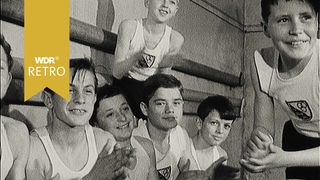 Schwarz-weiß Bild von Jungen in Turnkleidung, die in die Hände klatschen.