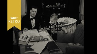 Schwarz-weiss: junger Mann sitzt am Tisch mit Keinkind und Baby im Hintergrund