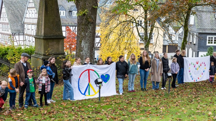 Junge Menschen stehen mit Friedensflagge in einer Reihe