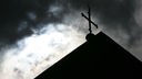 Symbolbild: Missbrauch Kirche, Kirchendach mit Kreuz und Wolken