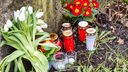 In der Nähe des Tatorts haben Trauernde Blumen und Kerzen an einem Stein abgelegt