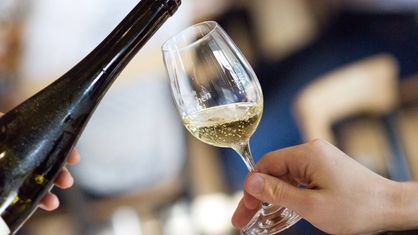 Weißwein wird in ein Glas ausgeschenkt