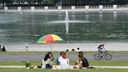 Eine Gruppe von Leuten sitzt unter einem Sonnenschirm am Aachener Weiher