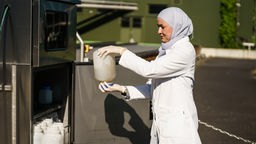 Eine Frau hält einen Behälter mit Abwasser in der Hand