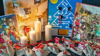 Adventskalender und Kerzen stehen auf einem Tisch