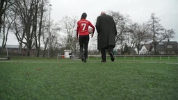 Spielerin mit der Nummer 7 läuft mit Moderator über das Fußballfeld