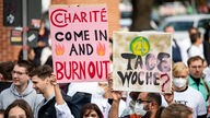 Ärzte stehen bei einem eintägigen Warnstreik des Marburger Bundes an der Berliner Charité mit Schildern mit der Aufschrift "Charité come in and Burnout" und "4-Tage-Woche ?"
