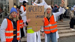 Ärztestreik in Köln: Menschen mit Schildern, Fahnen und Trillerpfeifen streiken vor der Uniklinik
