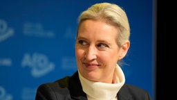 Alice Weidel lächelt vor blauen Hintergrund 