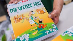Hände halten eine Ausgabe des neuen Asterix: Die weiße Iris