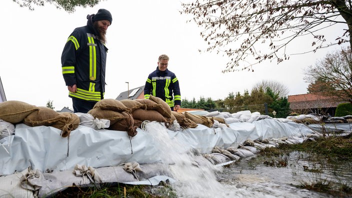 Einsatzkräfte betrachten die Sandsäcke als Schutz gegen Hochwasser