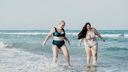 Zwei Frauen laufen durch das Wasser am Strand 