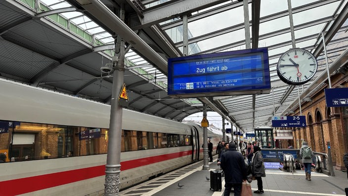 Menschen stehen am Gleis am Bahnhof Bonn, ein ICE steht bereit zur Abfahrt