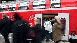 Bahnreisende steigen in Zug ein 