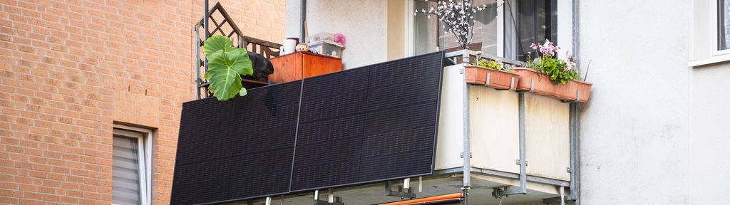 Solarmodule für ein sogenanntes Balkonkraftwerk hängen an einem Balkon.