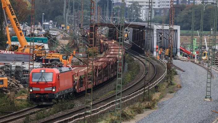 Ein Güterzug passiert eine Baustelle mit einem Schotterbett für neue Gleise.