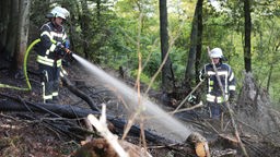 Zwei Feuerwehrkräfte löschen im Wald
