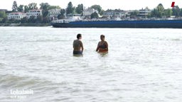 Zwei Badegäste, die hüfthoch im Rhein stehen