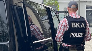 Polizist mit BKA Weste steht neben schwarzem Lieferwagen: Die Bundesanwaltschaft meldet die Festnahme von Terrorverdächtigen in Dortmund und Essen.