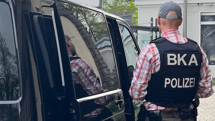 Polizist mit BKA Weste steht neben schwarzem Lieferwagen: Die Bundesanwaltschaft meldet die Festnahme von Terrorverdächtigen in Dortmund und Essen.