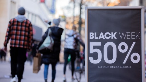Auf einem Aufsteller vor einem Geschäft in Köln steht "Black Week 50%" 