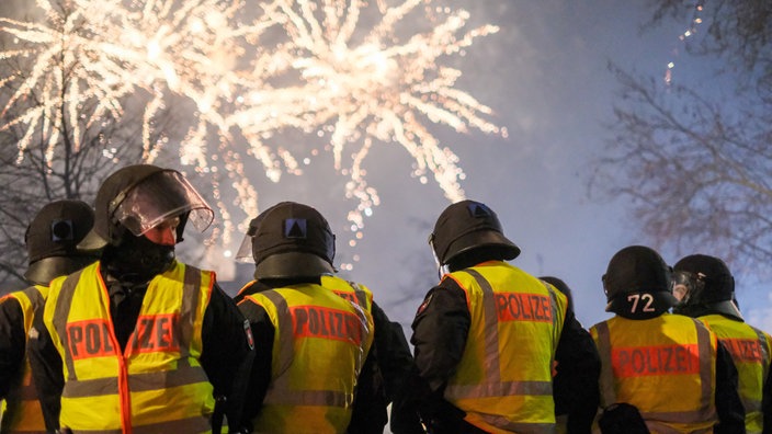 Polizisten im Silvestereinsatz, im Hintergrund Feuerwerk am Himmel