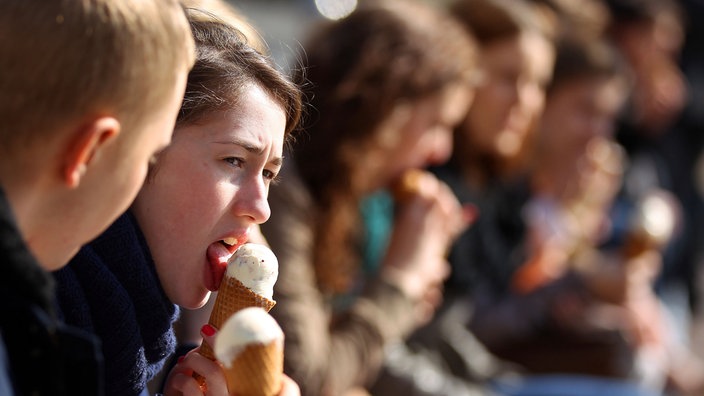 Studenten genießen am Dienstag in Bonn in der Frühlingssonne vor der Universität ein Eis