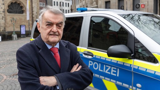 Herbert Reul neben einem Fahrzeug der Polizei auf dem Münsterplatz in Bonn im Rahmen der "Coffee with a cop"-Aktion am 13.03.2024