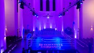 Ein Boxring in einer Kirche ist von lila Licht umgeben